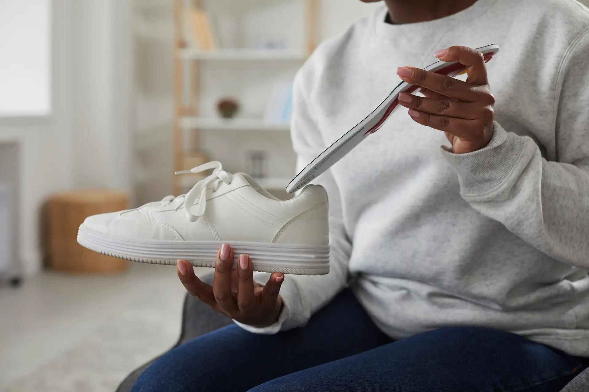woman inserting an insole into a sneakers at home close
