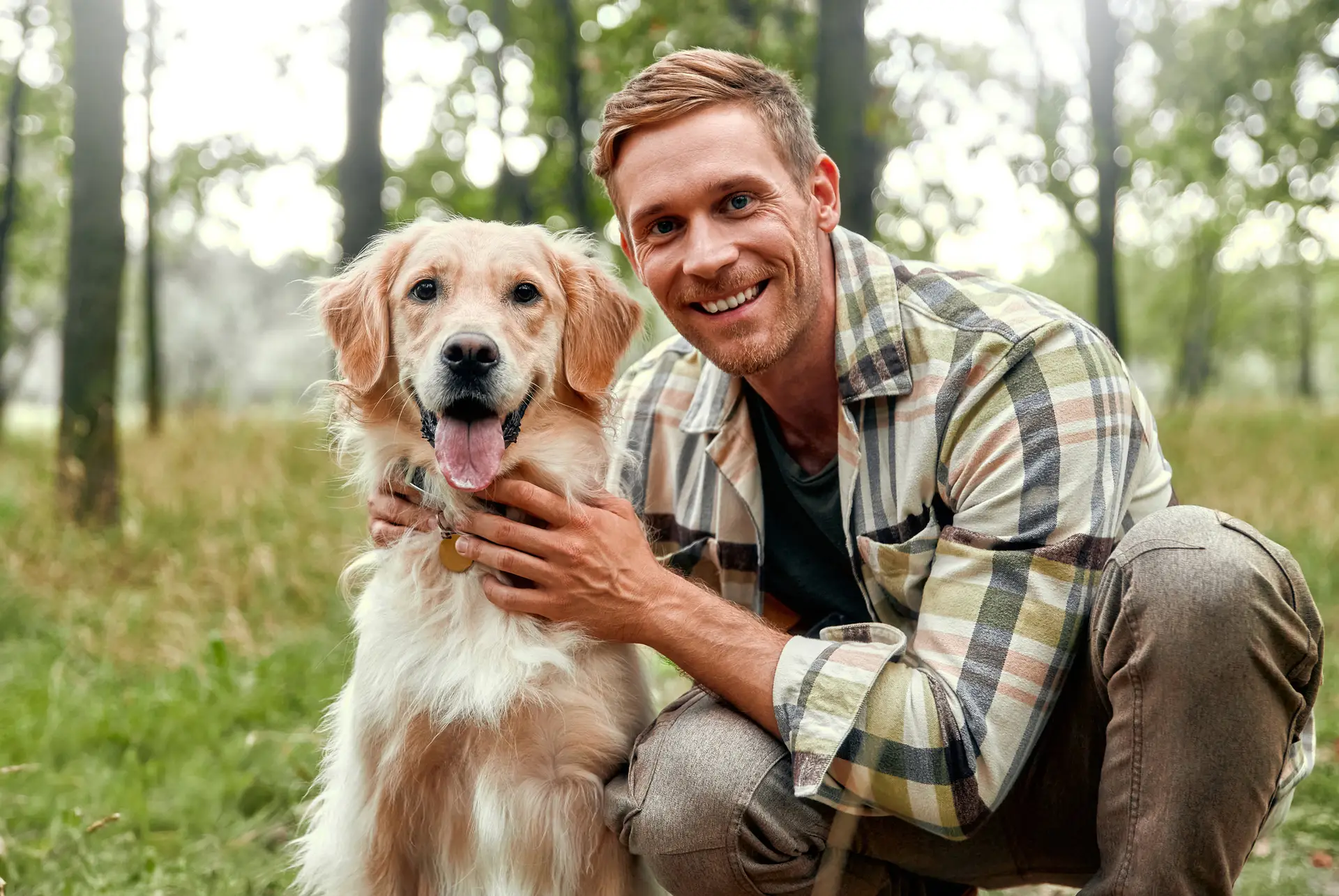 A cheerful man enjoys a delightful moment with his playful golden retriever in a lush forest
