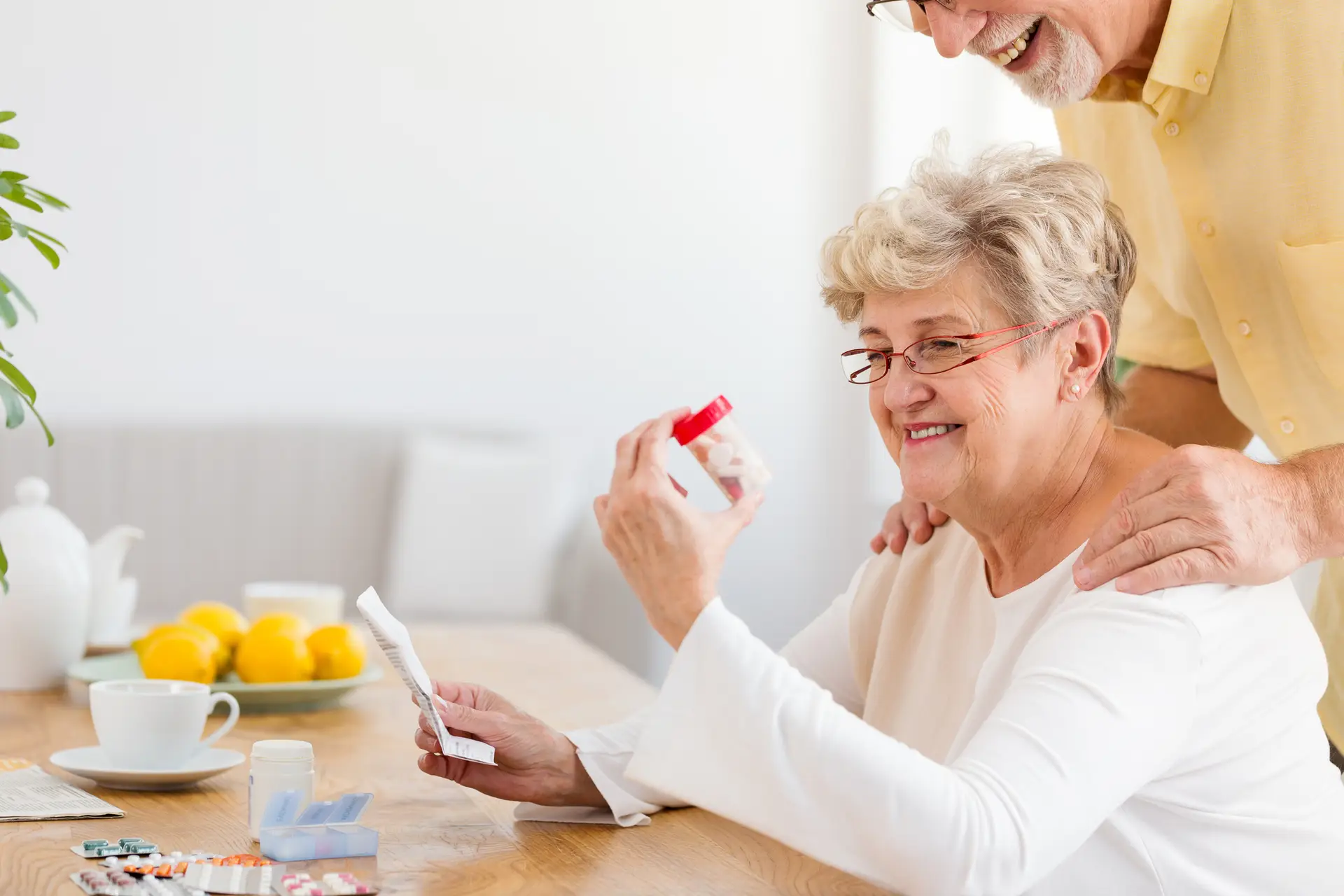 Smiling senior woman looking at container with drugs
