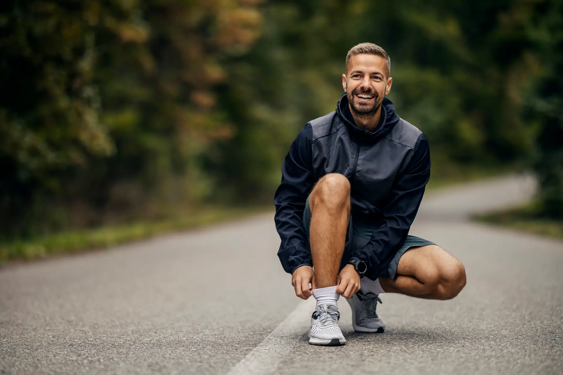 Man tying shoelaces before running outdoors, smiling